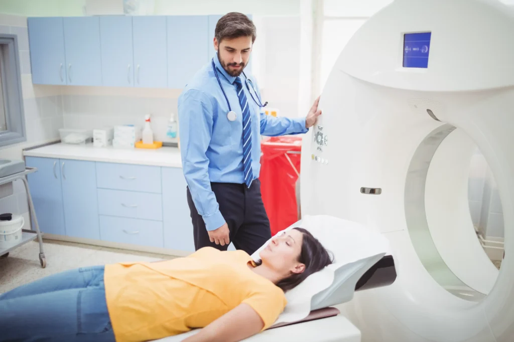 Doctor stands beside a patient preparing for an MRI scan, illustrating the use of diagnostic imaging to identify causes of back pain.