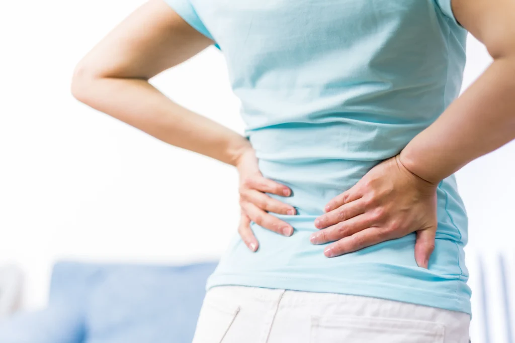 Person holding their lower back in discomfort, representing the topic of what chronic back pain is.
