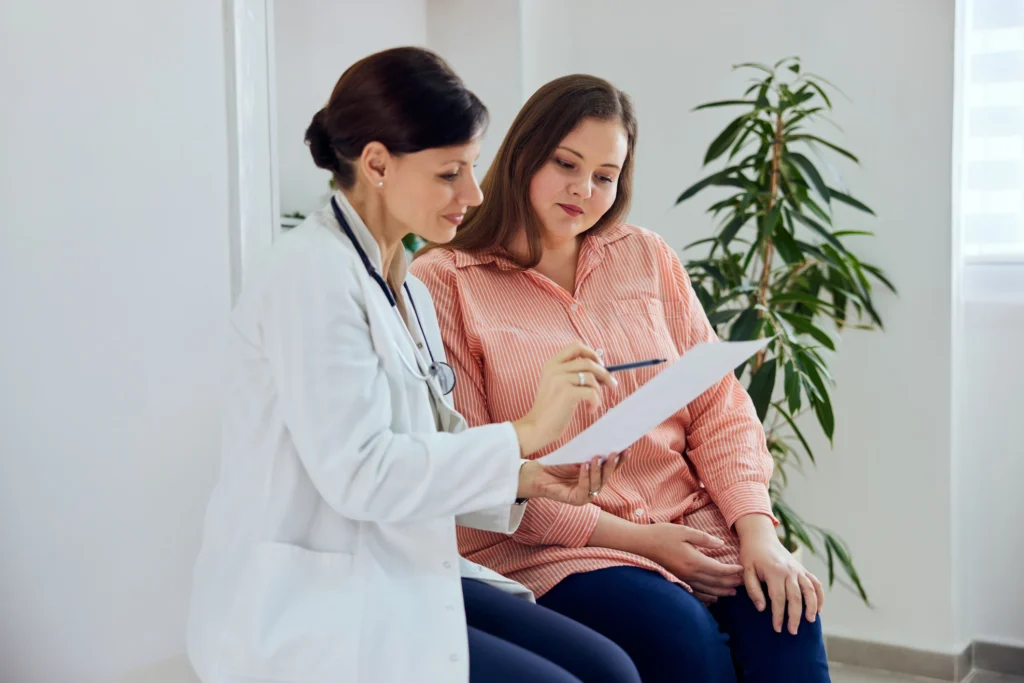 Female doctor reviewing paperwork with a patient in a medical office, representing what makes Pain & Spine Physicians of San Antonio different.
